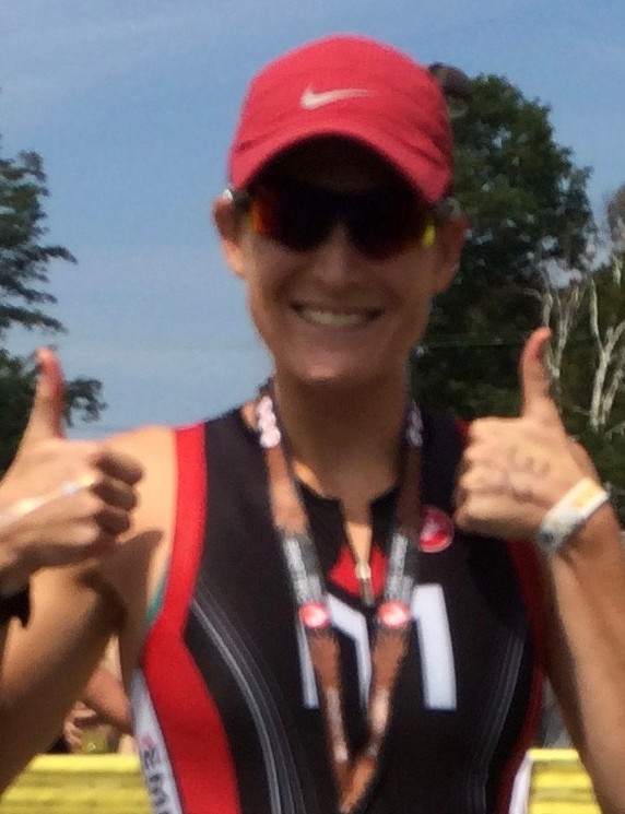 A woman giving two thumbs up while wearing a red hat.