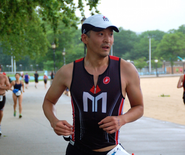 A man in black and white shirt running on street.