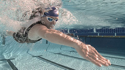 A person swimming in the pool with goggles on.