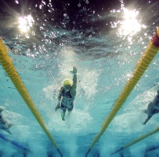 A person swimming in the water with two yellow poles.