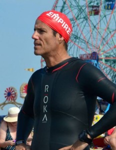 Athlete in wetsuit and swim cap outdoors.