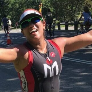 A woman in a triathlon suit is smiling.