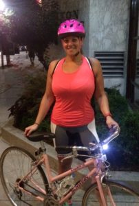 Woman in pink helmet with bicycle.