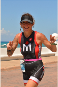 Smiling woman running in triathlon gear.