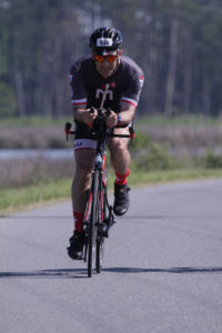 Cyclist in black gear riding outdoors.