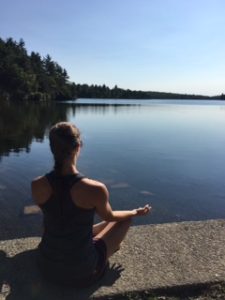 Person meditating by a calm lakeside.