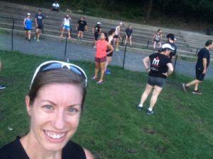 Group exercising outdoors with smiling woman.
