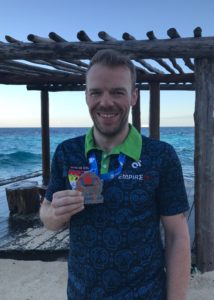 Man holding medal on a beach.