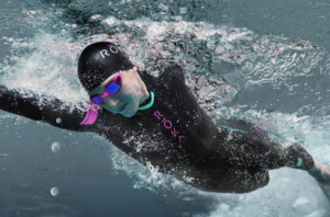 Swimmer in wetsuit and goggles underwater.