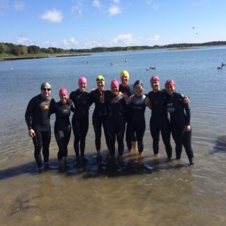 A group of people in wet suits standing on the beach.