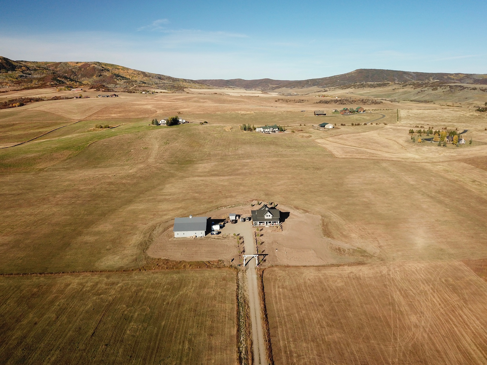 A farm with a barn and some buildings in the middle of an open field.