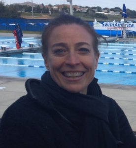Smiling person near outdoor swimming pool.