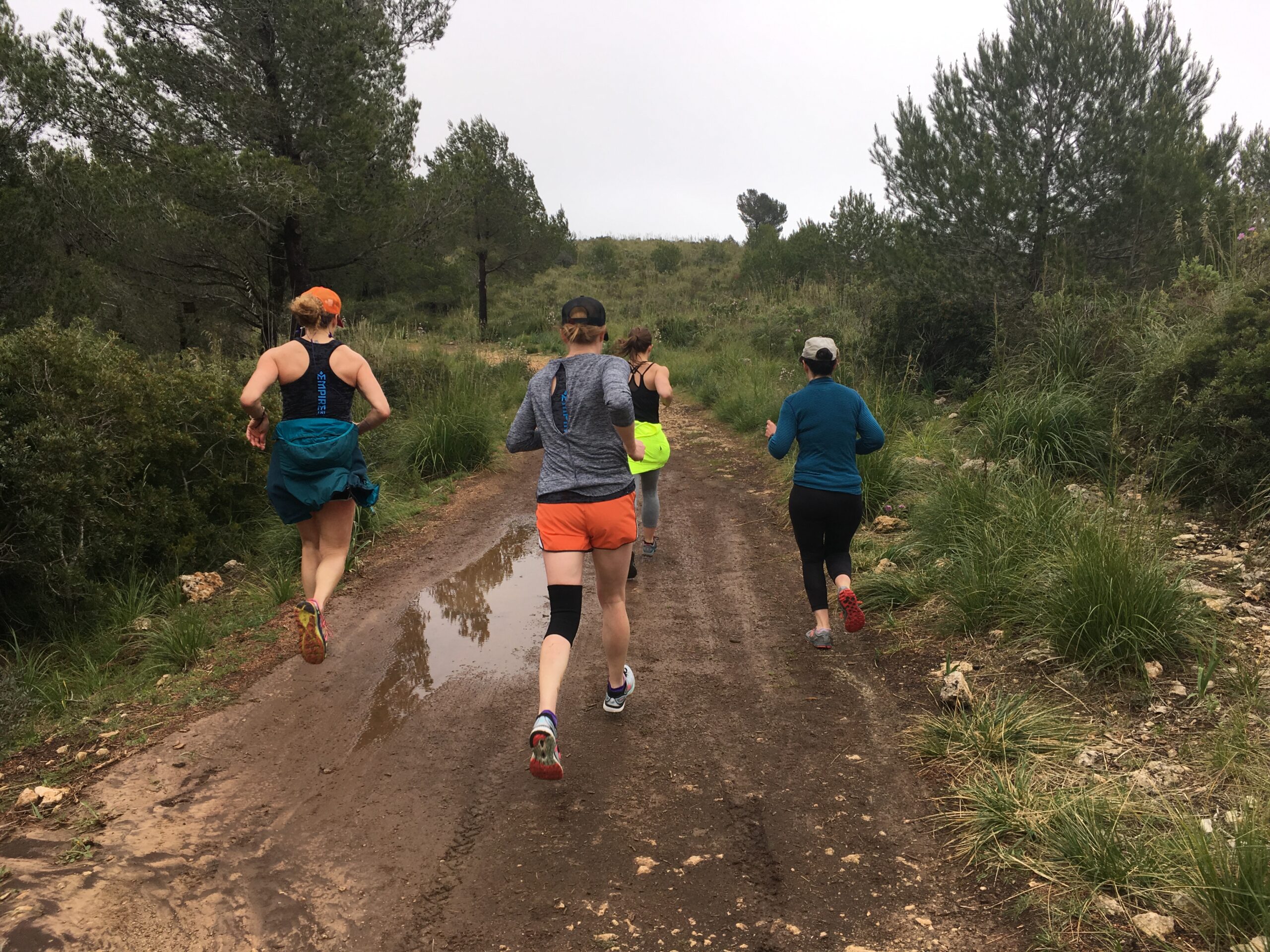 A group of people running on dirt road.