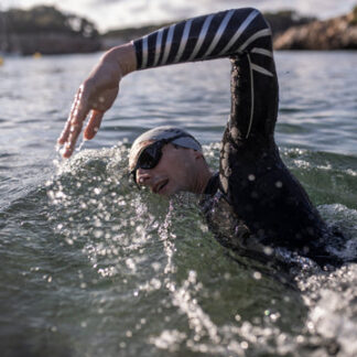 A person swimming in the water wearing a wetsuit.