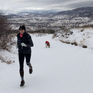 Two people running in the snow on a trail.