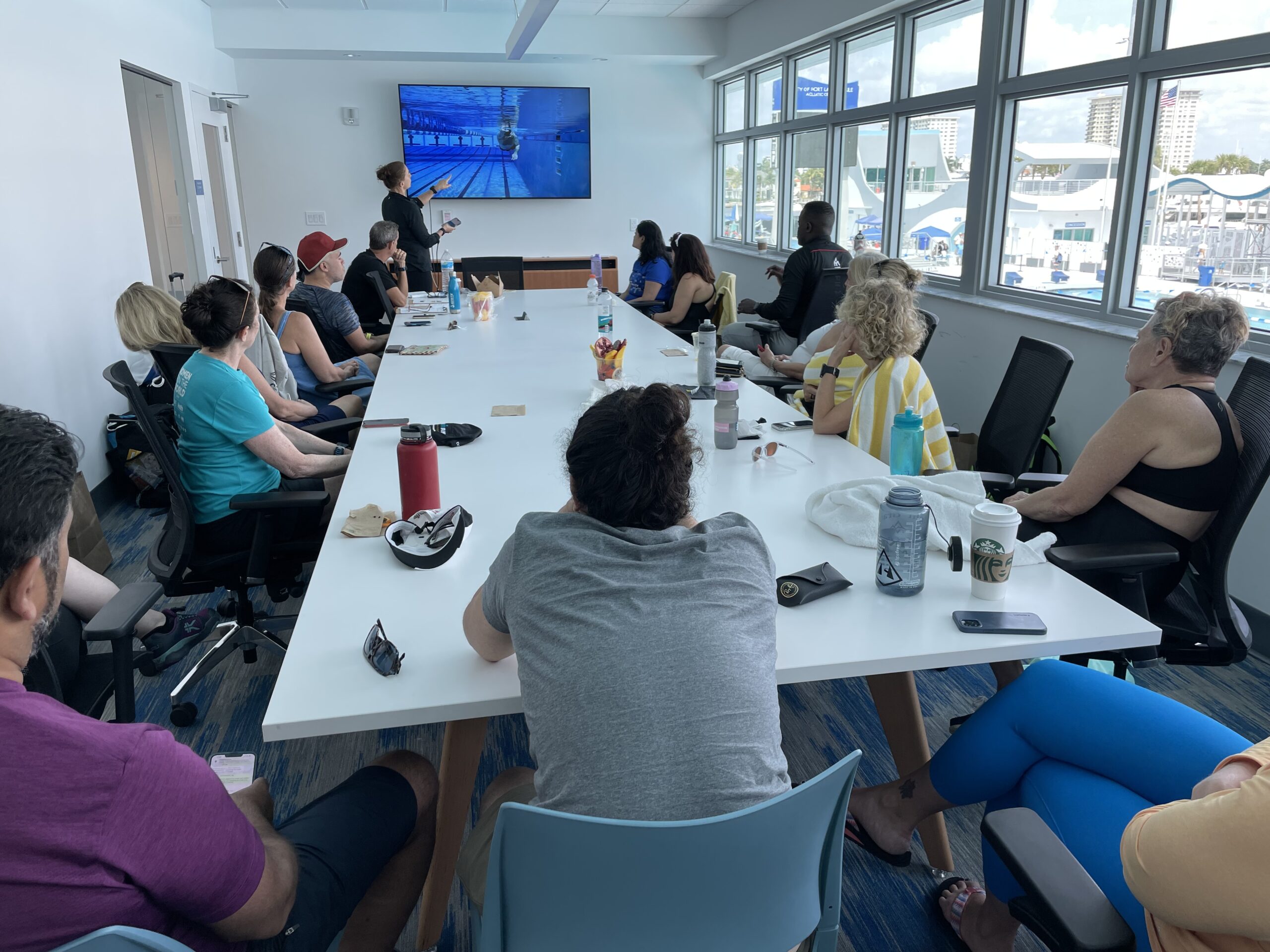 A group of people sitting at tables in front of a tv.