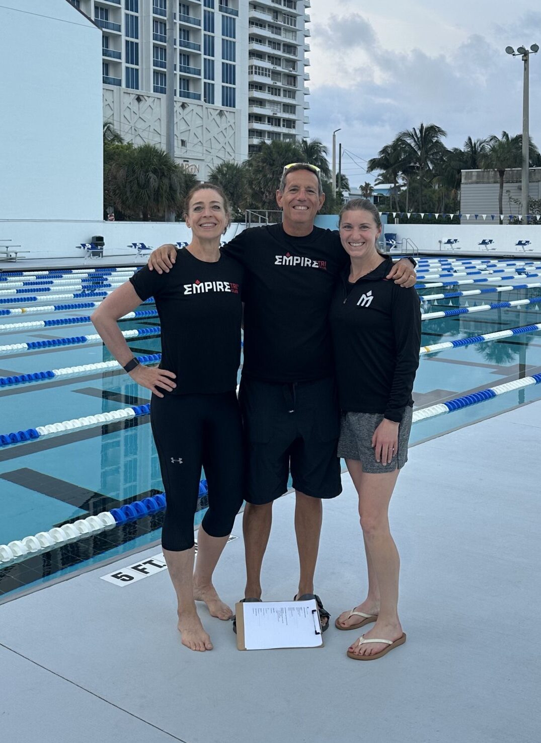 Three people standing in front of a pool.