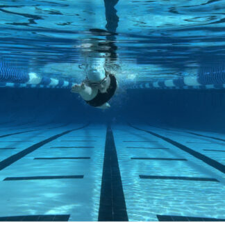 A person swimming in an indoor pool under water.