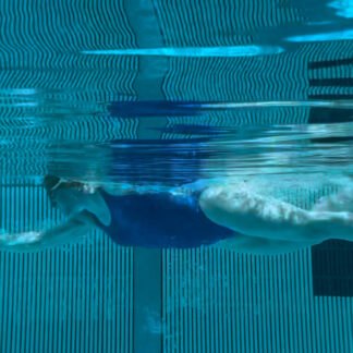 A person swimming in the pool with blue water.